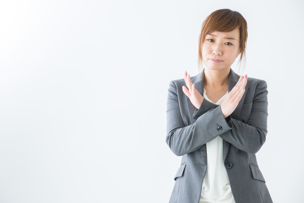 両手でバツ印をする女性
